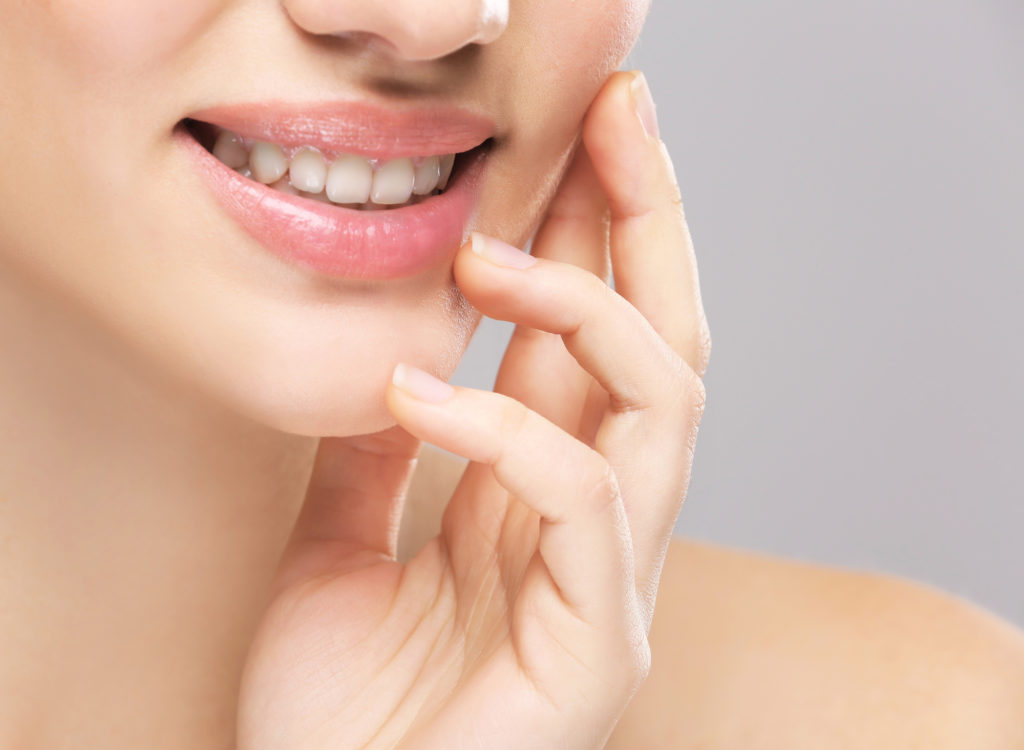 Face of young woman on light background